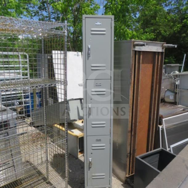 Global metal employee locker system with 3 lockers, 12x15x78 inches. Gray finish, used condition, outdoor setting.
