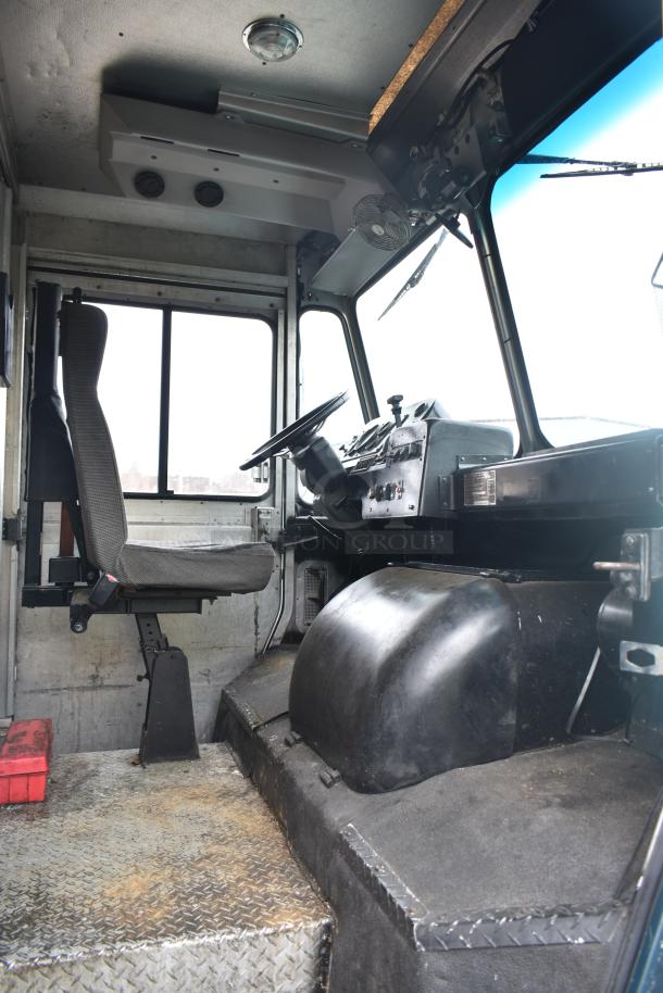 Interior of a 2002 Freightliner MT45 food truck driver's cabin, featuring a steering wheel, driver's seat, and control panel.