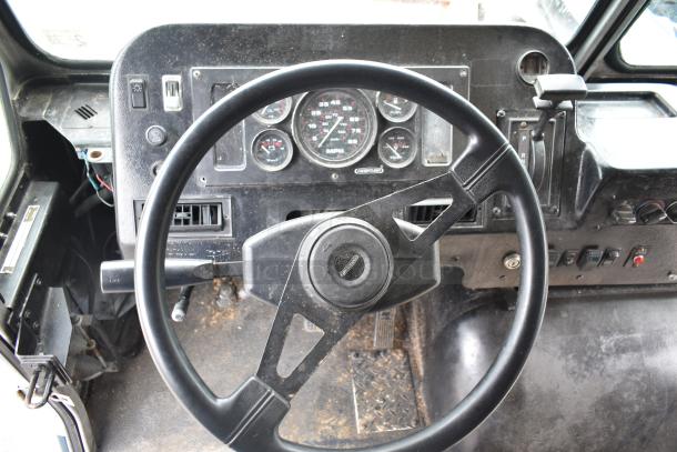 Steering wheel and dashboard of a 2002 Freightliner MT45 food truck, showing gauges and gear shift, somewhat worn condition.