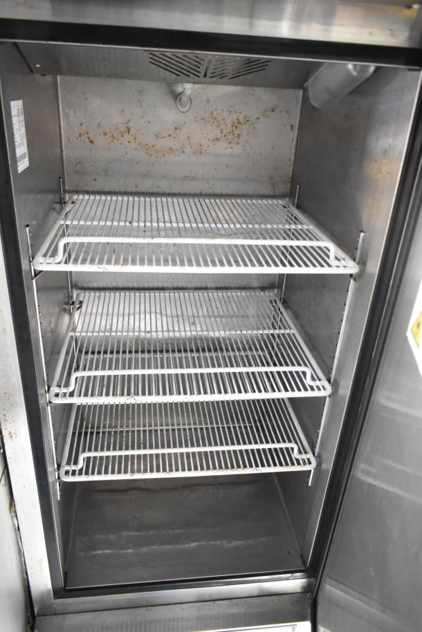 Industrial refrigerator interior with three wire shelves, showing signs of rust and wear. Ideal for food truck use.