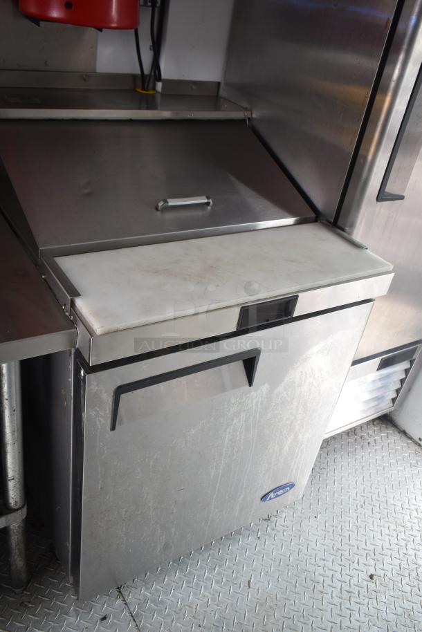 Stainless steel refrigeration unit inside 2002 Freightliner MT45 food truck, featuring a cutting board top and visible wear.