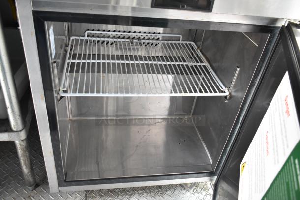 Interior view of refrigeration unit inside 2002 Freightliner MT45 food truck, featuring steel shelving and open door.