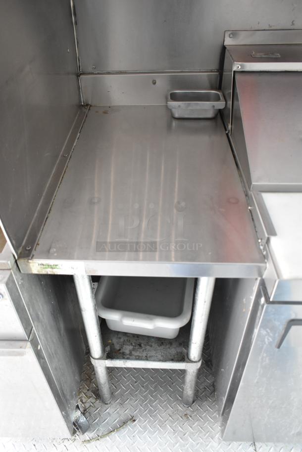 Interior view of 2002 Freightliner MT45 food truck kitchen, featuring stainless steel prep counter and metal flooring.