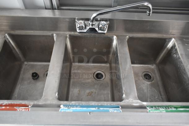 Interior view of a 2002 Freightliner MT45 food truck featuring a stainless steel triple sink with faucet, labeled for washing, rinsing, and sanitizing.