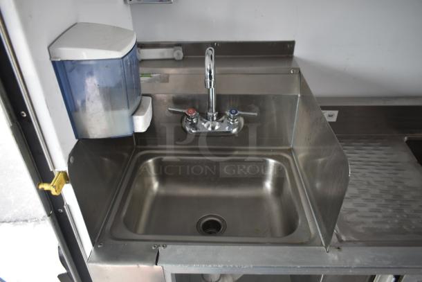 Stainless steel kitchen sink in 2002 Freightliner MT45 food truck. Features faucet, soap dispenser, and counter space.