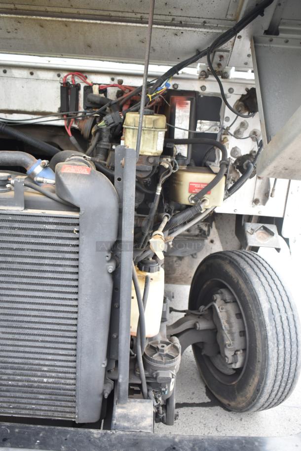 Engine bay of a 2002 Freightliner MT45. Visible components include radiator, hoses, and wiring. Dust and wear evident.