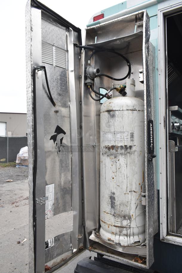 2002 Freightliner MT45 food truck propane tank compartment with hookup, seen with open door and visible wear.