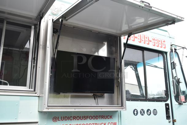 2002 Freightliner MT45 food truck with serving window, Ludicrous wrap, screen, and social media handles.