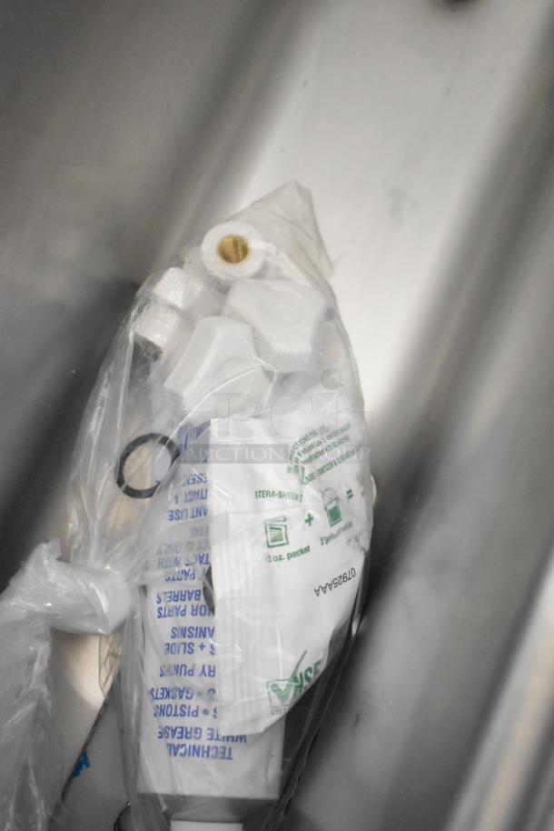 BRAND NEW Frosty Factory 217W commercial frozen cocktail machine parts in a sealed plastic bag, visible labels indicate cleaning instructions and part identification.