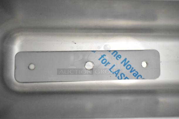 Metal surface with mounting holes and partially visible label on a Frosty Factory 217W frozen cocktail machine.