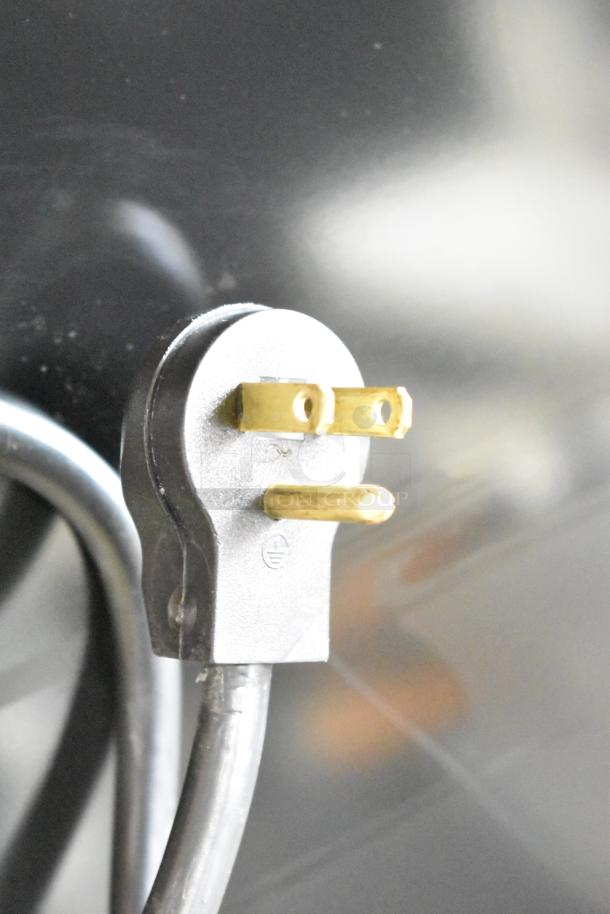 Close-up of a power cord plug for a Beverage Air MT23-1 B 18 commercial merchandiser, black surface background.