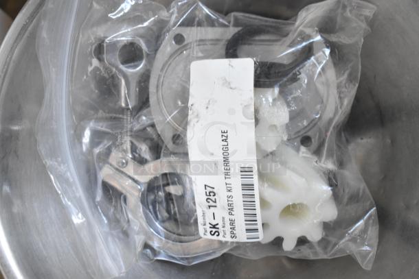 A spare parts kit labeled "SK-1257" for Thermoglaze, sealed in a clear plastic bag, containing various plastic and metal components.