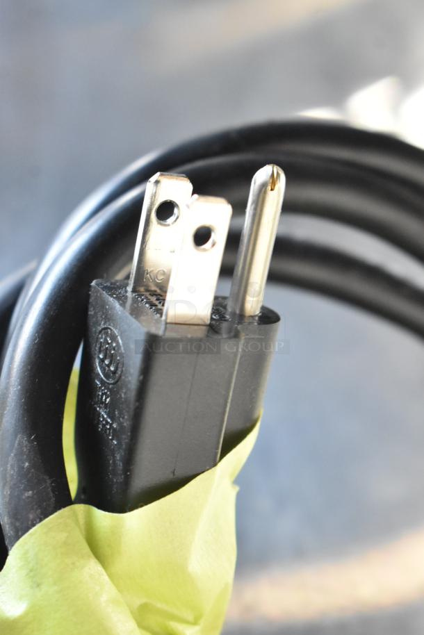 Close-up of a power plug for the Sharp R-21LVF commercial microwave oven. Black cord coiled with yellow tape.