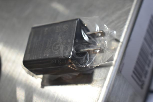 Plastic-wrapped power adapter, part of the Mettler Toledo BC Countertop Scale, showing electrical plug and certification markings.