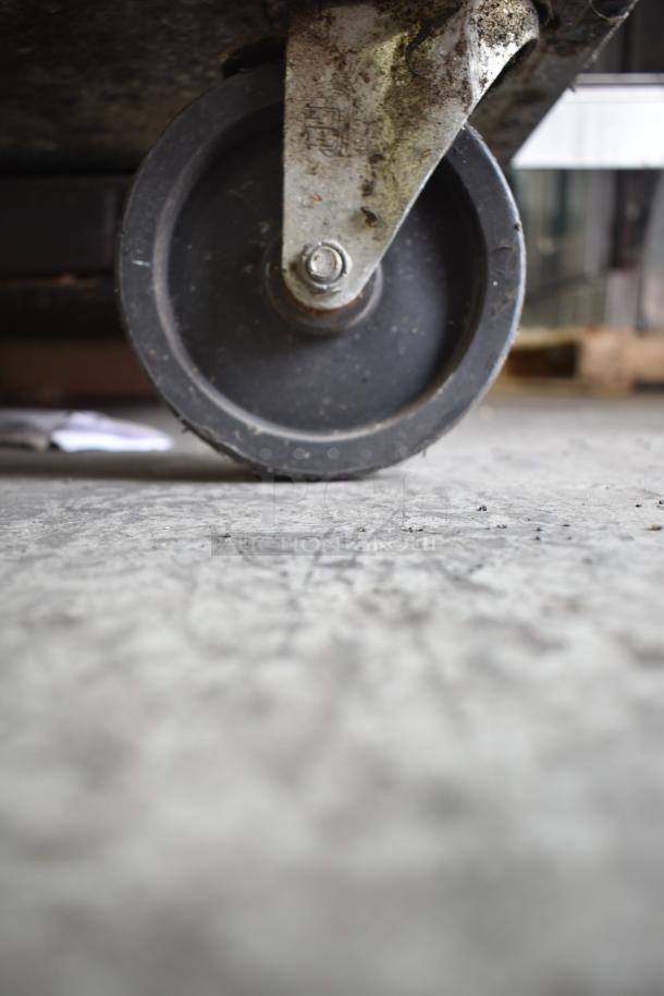 Close-up of a commercial caster wheel on a True TRCB-36 chef base. Caster shows wear, indicating use.