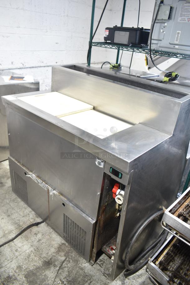 Commercial stainless steel prep table, 115 volts, 1 phase, with cutting board surface, good condition, visible control switches.