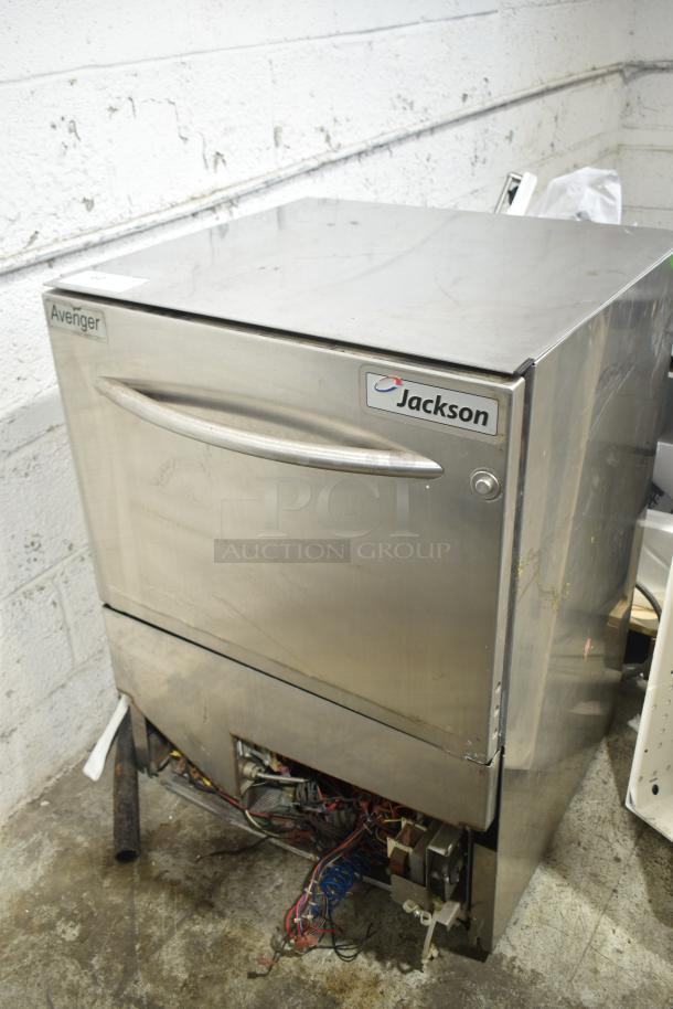 Jackson Avenger undercounter dishwasher, stainless steel, visible wear, labeled "Jackson" and "Avenger".