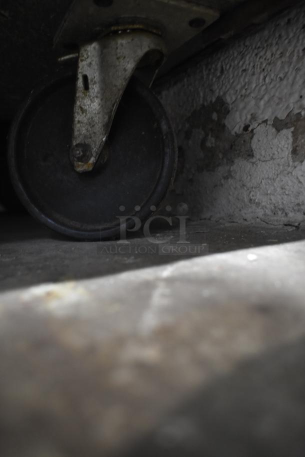 Close-up of a caster wheel on the True TSSU-72-30M-B-ST commercial prep table, showing wear and functional condition.