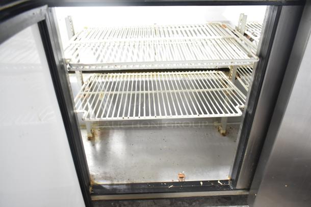 True TSSU-72-30M-B-ST commercial sandwich prep table interior with wire shelves, showing some wear and residue.