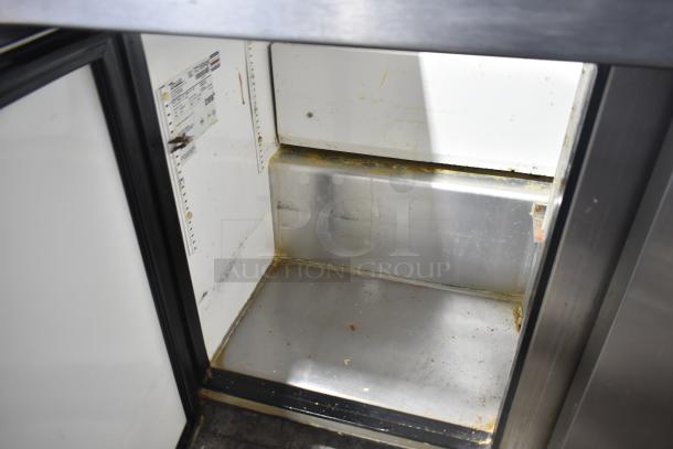 True TSSU-72-30M-B-ST commercial sandwich salad prep table interior, visible wear, includes model and serial number plate.