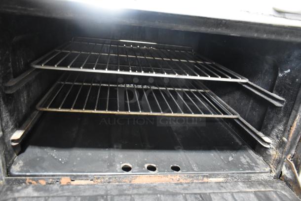 Garland commercial gas 4-burner range with oven, over shelf, and backsplash. Features include two oven racks. Good condition.