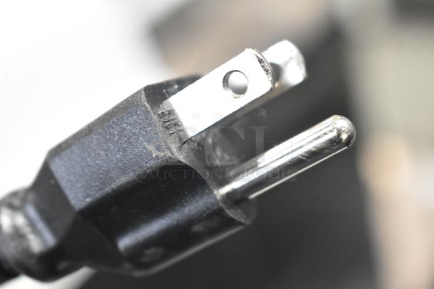 Epson WorkForce WF-7840 power plug close-up, showing a standard three-prong connector, black casing, slight wear visible.