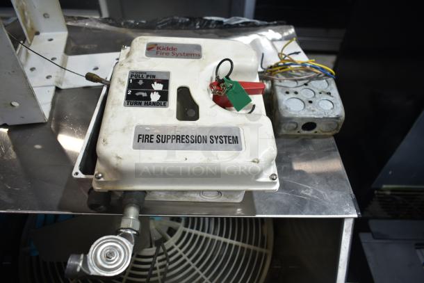 Kidde Fire Suppression System with wiring and metal base, visible "Pull Pin" instructions and "Fire Suppression System" label.