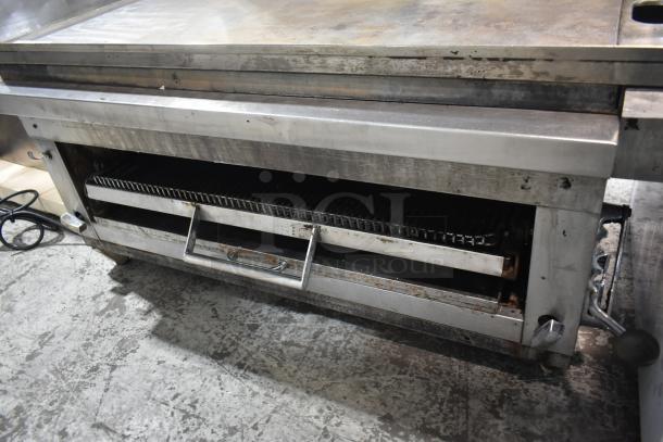 Commercial gas-powered flat top griddle with cheese melter, stainless steel, showing moderate wear. Ideal for restaurant use.