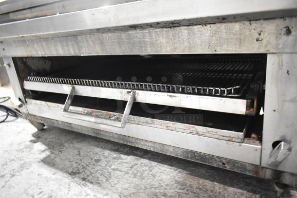 Commercial gas-powered flat top griddle with cheese melter, featuring a sturdy metal construction and visible wear, ideal for high-volume kitchens.