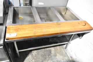 Commercial 3 well steam table with butcher block cutting board, under shelf, good condition. Visible tag "75."