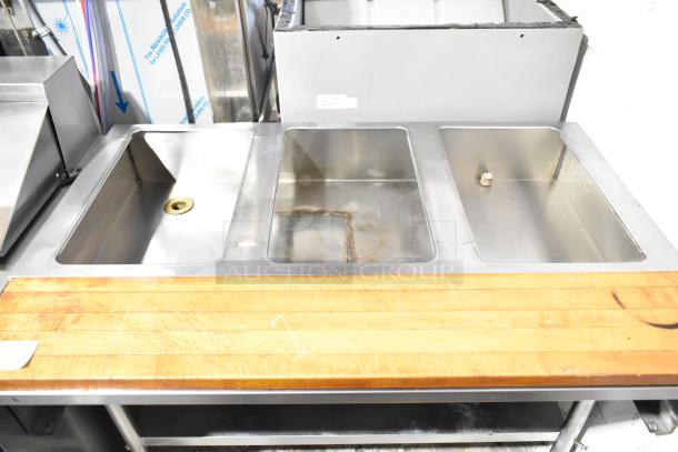 Commercial 3-well steam table with stainless steel finish, butcher block cutting board, and under shelf in used condition.