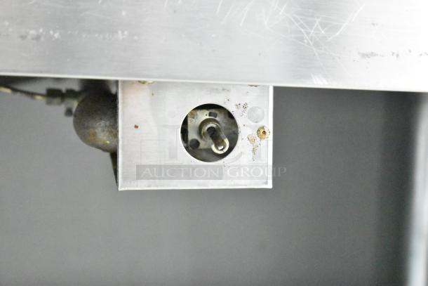Alt text: Commercial 3-well steam table control detail, with visible wear and scratches, featuring stainless steel construction.