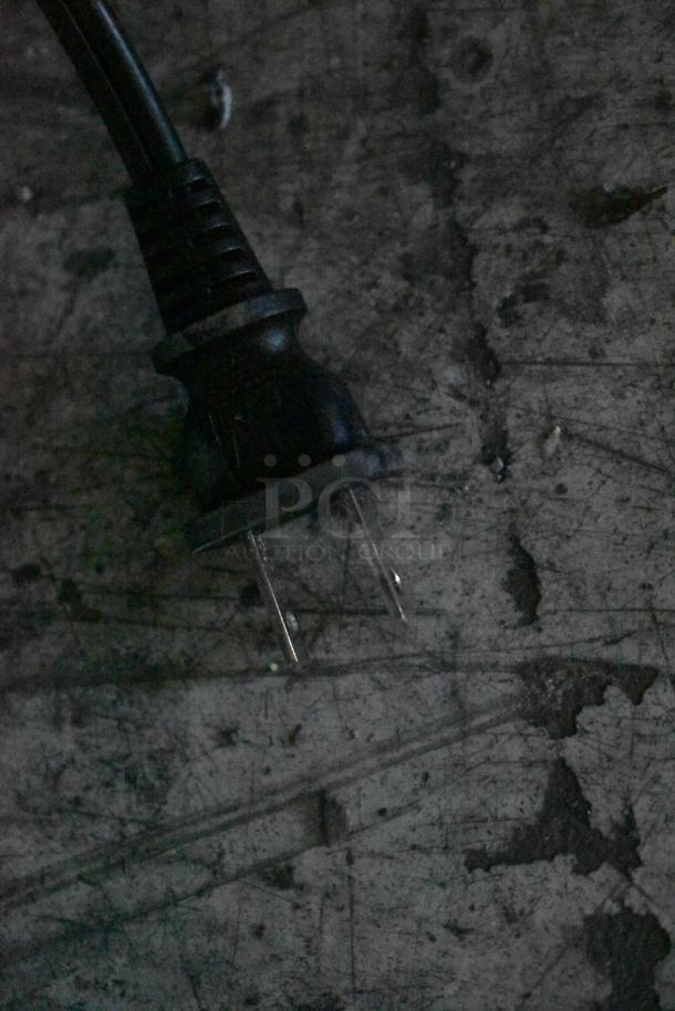 Close-up of a black plug for the HP Smart Tank 7602 printer, showing standard 120V, 1-phase configuration.