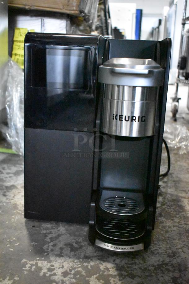 Keurig single cup coffee machine, black and silver, countertop model, marked with "Keurig," 120 volts, 1 phase.