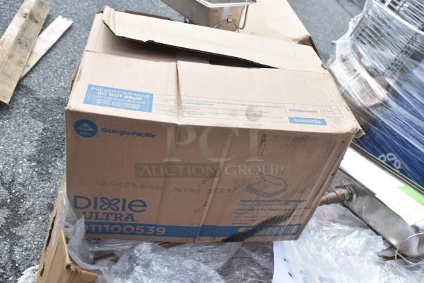 Cardboard box labeled Dixie Ultra 01100539 by Georgia-Pacific, contains scratch and dent items, box slightly open and on pavement.