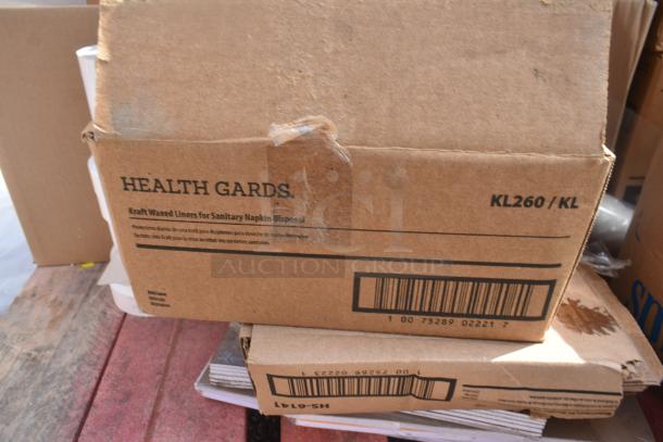 Cardboard box labeled "Health Gards KL260/KL," containing scratch and dent items, including liners for sanitary napkin disposal.