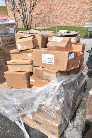 Boxes of assorted kitchen items including ladles, plates, and a faucet, labeled "Scratch & Dent." Pallet wrapped in plastic.