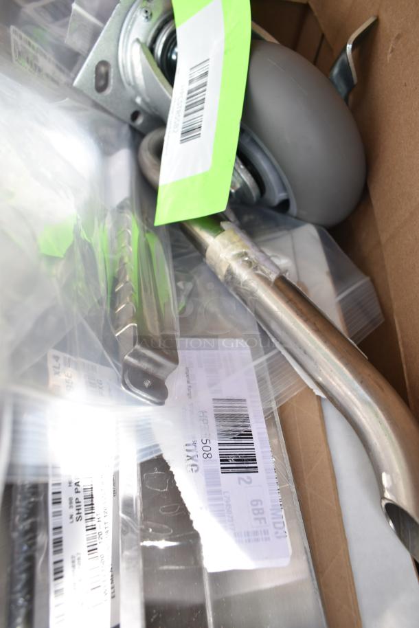 Assortment of new scratch and dent items including metal parts and a wheel, with visible shipping labels and barcodes.