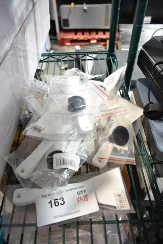 18 new scratch and dent items, including white plastic scrapers and black knobs, packaged in clear plastic bags. Auction label "163 QTY 18".