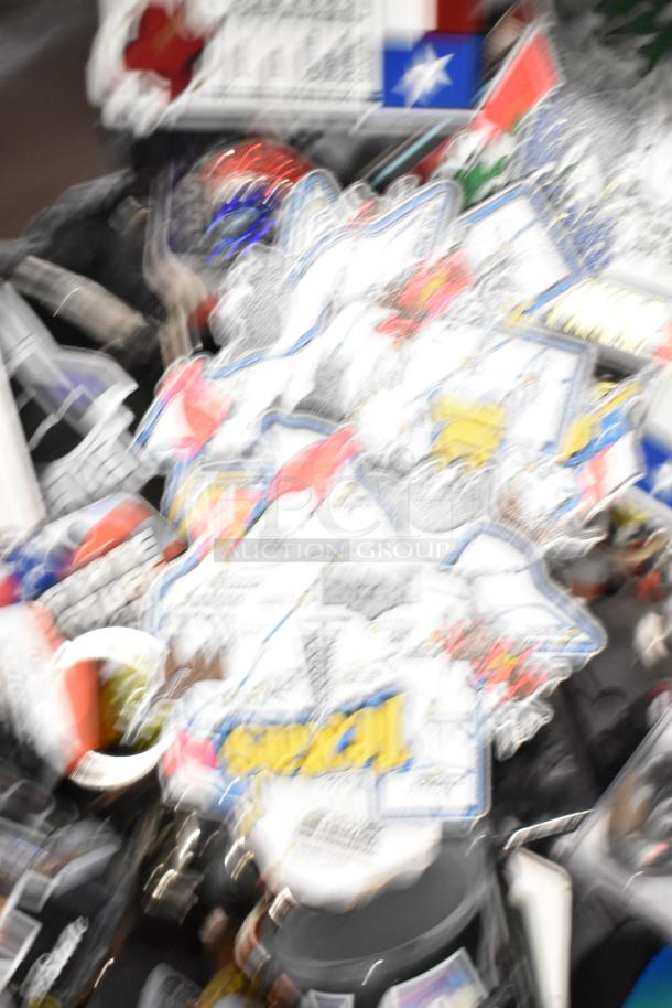 Blurry image of a lot of Texas-themed items, including various pins, a spoon, and shot glasses. Various visible symbols.