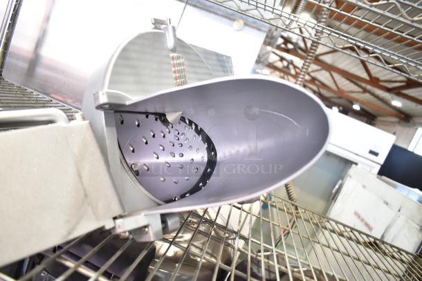 Commercial pelican head with grating blade, in good condition, placed on metal shelving, showing interior view.