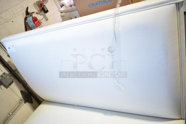 White double-sided booth seat with minor surface imperfections, item tag 105. Durable upholstery, versatile for dining spaces.