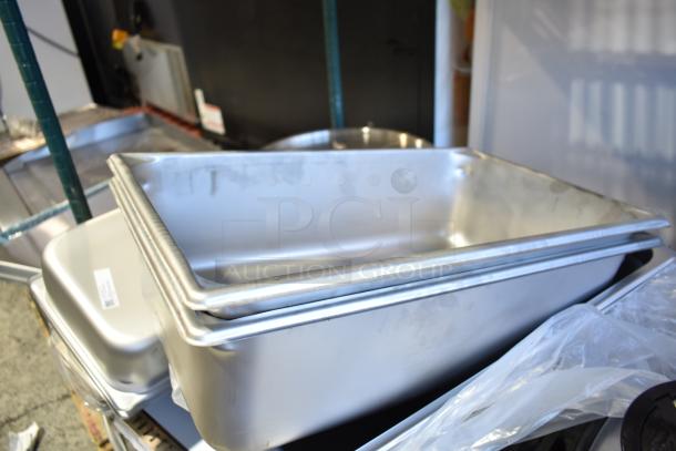 Stack of new aluminum and stainless steel steam table pans, varying sizes, with visible anti-jam design.