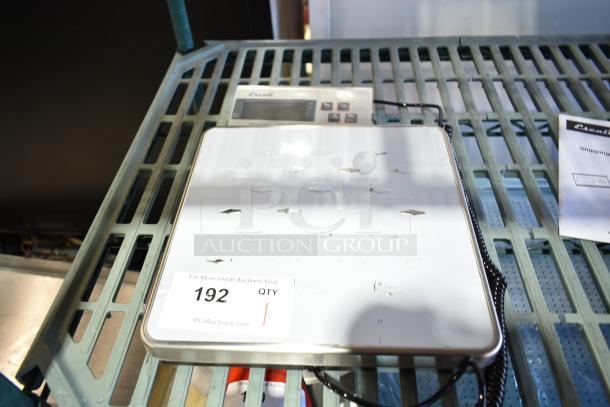 Brand new Escali 120S countertop scale with visible scratches and dents, LCD screen, and operational buttons. Auction tag number 192.