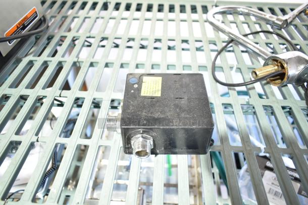 8 various items including 020237-45 power unit on a metal grid. Power unit shows minor wear, with visible connectors and label.