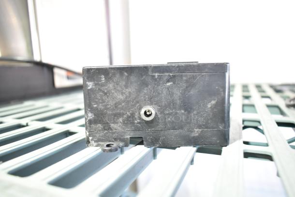 Black power unit, model 020237-45, moderate wear, placed on a metal grid. Includes seven additional items.