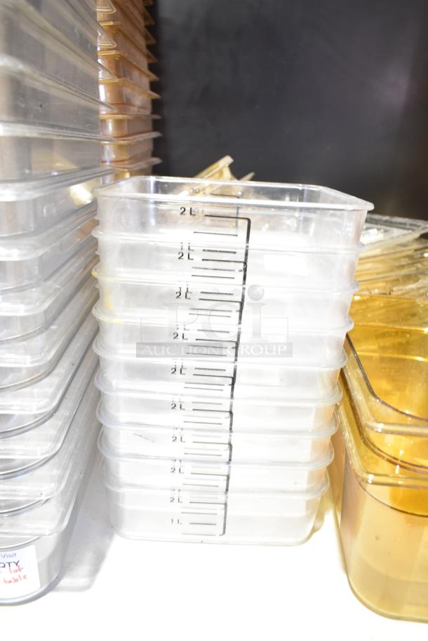 Stacked transparent 2L containers with measurement markings, alongside various bins and lids, in good condition.