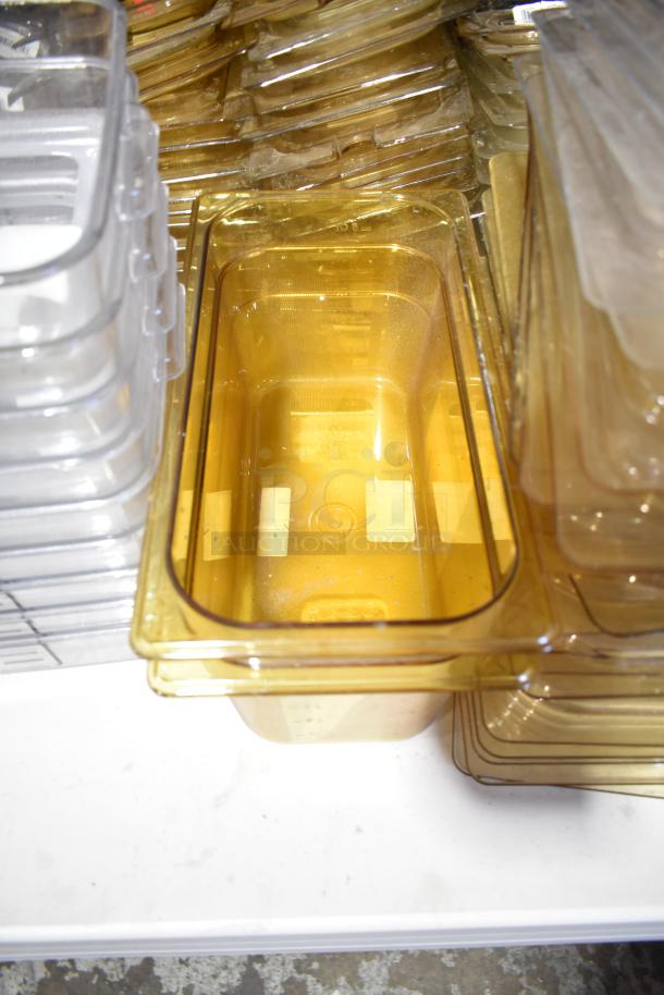 Lot of various plastic containers, drop-in bins, and lids. Items show light use with some scuffing, clear and amber colors.