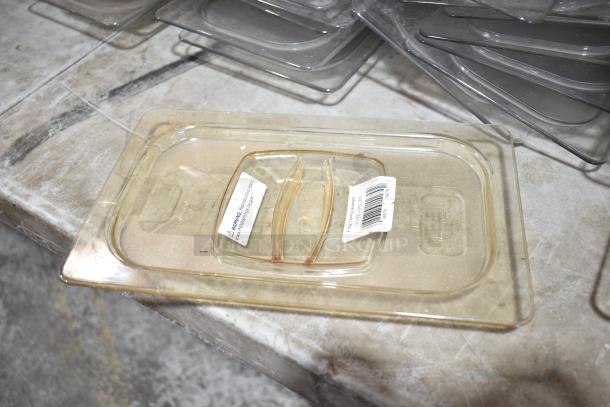 Lot of plastic drop-in bin lids, some with labels and barcodes, stacked on a concrete surface. Used condition.