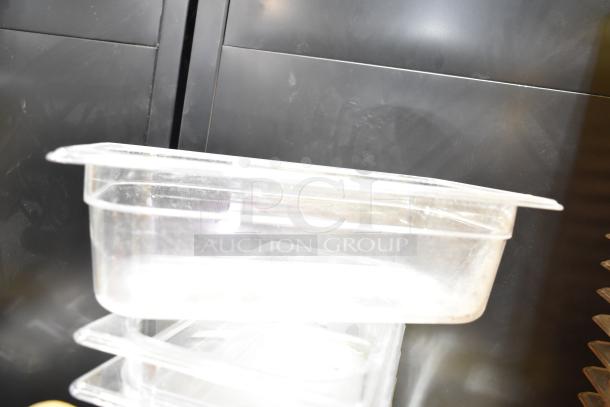 Transparent plastic drop-in bins stacked with lids, in fair condition. Dust visible; ideal for storage use.